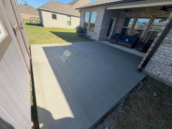 New concrete back patio slab behind a house with a covered porch and blue chairs, Long Beach