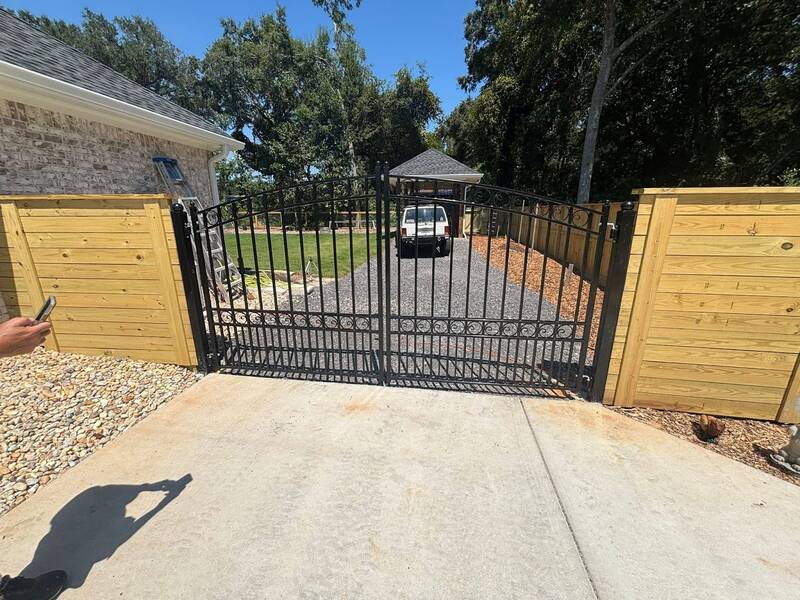Horizontal-board wood privacy fence beside a black metal double driveway gate