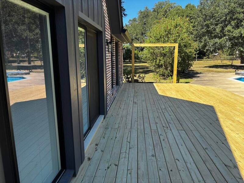 New unstained wood deck along a house, next to a pool