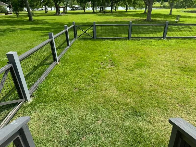 Wire-panel fence in a dark gray wood frame with an X-braced gate on a green lawn